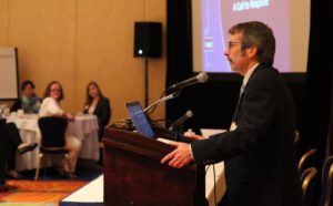 A photo of Eric Davidson, PhD, speaking at a podium during a workshop event on sexual harassment